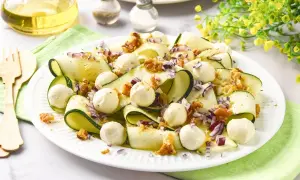 Deliciosa ensalada de calabacín en cintas, con bolitas de mozzarella, nueces y cebolla morada. Un plato fresco y ligero.