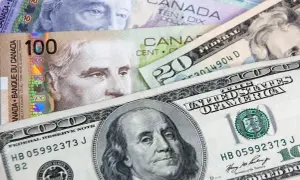 Kanadyjski dolar i amerykańskie banknoty, w tym 100 dolarów kanadyjskich i 100 dolarów amerykańskich, tworzą finansową mozaikę.