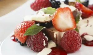 Ein köstlicher geeister Kaiserschmarrn mit frischen Beeren, Erdbeeren und Himbeeren, garniert mit Minze und einer cremigen Sauce.
