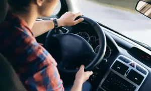 Mężczyzna w kratę prowadzi auto. Zastanawiasz się, co to jest amortyzacja samochodu? To proces zużywania się pojazdu.