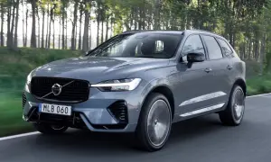 Szary Volvo XC60 z napędem hybrydowym, poruszający się po leśnej drodze. Dostępne różne silniki.