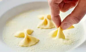 Hand formt Farfalle-Nudeln in einer Schüssel mit Grieß.