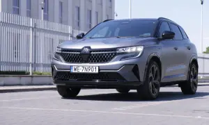 Nowy Renault Austral w matowym, szarym kolorze prezentuje się elegancko na tle nowoczesnego budynku.