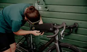 Osoba montuje torbę podsiodłową do roweru. Przygotowania do składania roweru przed wyprawą.
