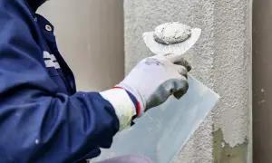 Pracownik nakłada tynk silikonowy na ścianę. Sprawdź atrakcyjną cenę za m2 robocizny.