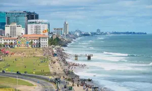 Kolombo, Sri Lanka na własną rękę: tętniące życiem wybrzeże z ludźmi spacerującymi po plaży i zielonym parku, nowoczesne budynki i ocean z falami.