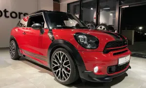 Czerwony mini paceman z czarnymi pasami i felgami stoi w salonie.