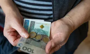 Dłonie trzymają banknoty 50 i 100 zł oraz monety. Czy to odzwierciedla średnią emeryturę w Polsce?