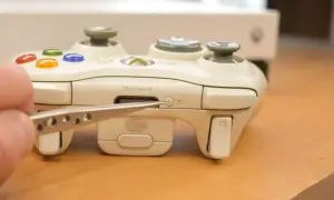 Biały kontroler Xbox z pęsetą wskazującą na przycisk synchronizacji.