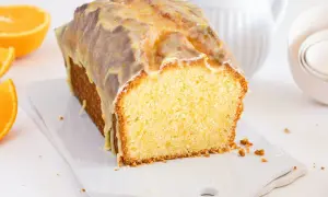 Bizcocho de naranja y chocolate cubierto con glaseado, con rodajas de naranja al lado.