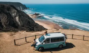 Ein Campervan steht am Rand einer Klippe mit Blick auf den Ozean. Perfekt für einen roadtrip portugal 10 tage.