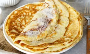 Ein Stapel goldbrauner Pfannkuchen, bestreut mit Zucker. Ein einfaches Pfannkuchen Rezept für jeden Tag.