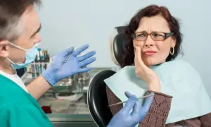 Dentysta wyjaśnia pacjentce, na czym polega zatrucie zęba, która odczuwa silny ból.