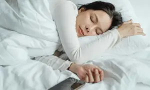 A woman sleeps peacefully, perhaps a natural short sleeper, with her phone nearby.