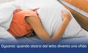 Persona rannicchiata sotto le coperte, con la testa affondata nel cuscino. La difficoltà ad alzarsi la mattina può essere un sintomo di disania.