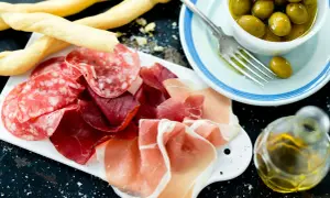 En härlig italiensk tapasbricka med salami, prosciutto, grissini, oliver och olivolja. Perfekt för en mysig kväll.