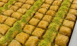 En stor bricka med gyllene, saftiga baklava-bitar, strödda med gröna pistagenötter. Perfekt för ett baklava recept.