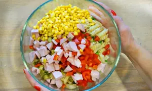 Bunte Zutaten für ein leckeres Nudelsalat Rezept: Mais, Paprika, Wurstwürfel, Erbsen und Spiralnudeln in einer Glasschüssel.