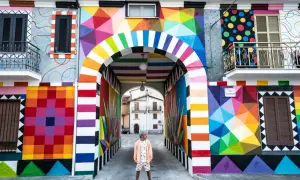 Un uomo in piedi sotto un arco colorato, un'esplosione di arte urbana che celebra l'Italia, patria della bellezza.