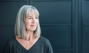Een vrouw met grijs haar kijkt peinzend weg. Ze straalt een rustige kracht uit, wat kan passen bij de complexiteit van autisme bij vrouwen.