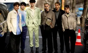 Sechs junge Männer präsentieren modische Outfits. Einer trägt einen schwarzen Blazer, der elegant zu kombinieren ist.