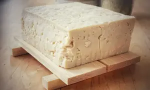 Duży blok domowego, białego tofu na drewnianej podstawce.