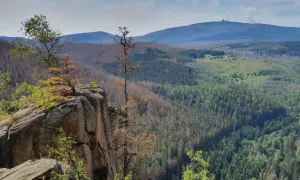 Felsformation an der Rabenklippe im Harz mit Blick auf bewaldete Hügel und den Brocken im Hintergrund.