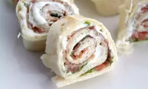 Rouleaux de pain de mie garnis de fromage frais et de jambon, coupés en tronçons pour un apéritif gourmand.
