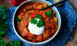 Herzhaftes Bauerntopf Rezept mit Hackfleisch, Kartoffeln und Paprika, garniert mit einem Klecks Sauerrahm und Petersilie.