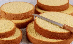 Dischi di pan di spagna dorati e soffici, pronti per essere farciti. Un coltello da torta è appoggiato su uno strato.