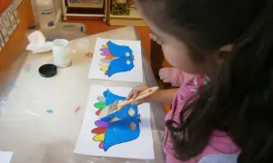 Niña pinta pájaros de colores, preparándose para un día de la paz para niños.