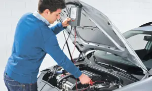 Uomo effettua manutenzione batteria auto con un tester Bosch.