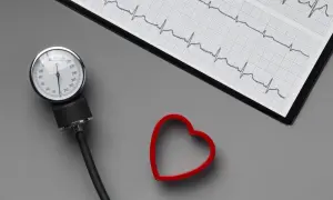 Ciśnieniomierz, EKG i czerwone serce na szarym tle.