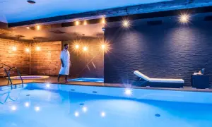 Mężczyzna w szlafroku spaceruje po luksusowej strefie dla dorosłych z basenem i jacuzzi.