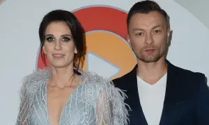 Sylwia Grzeszczak i Liber pozują do zdjęcia. Ona w błyszczącej sukni z piórami, on w granatowej marynarce.