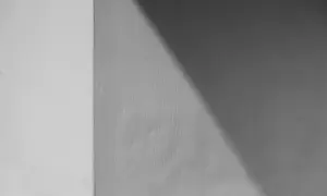 Ściana z widocznym podziałem na jaśniejszą i ciemniejszą część, o chropowatej fakturze. Wygląda jakby użyto klej zamiast tynku zewnętrznego.