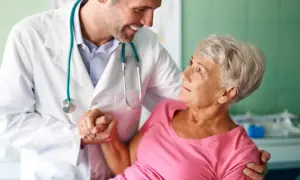 Lekarz w białym kitlu wspiera starszą pacjentkę. To przykład troski w geriatrii, która zajmuje się zdrowiem seniorów.