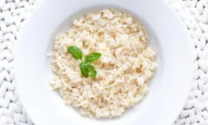 Jak ugotować ryż: pyszny ryż z parmezanem i bazylią na białym talerzu.