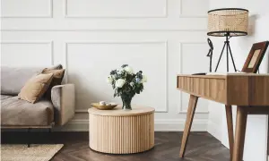 Elegancki salon glamour z dominującym drewnem. Miękka sofa, okrągły stolik i biurko tworzą przytulną przestrzeń.