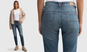 Modelka w beżowym kardiganie i białej bluzce prezentuje jeansy: spodnie szerokie w udach, wąskie w łydkach.