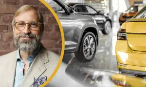 En leende man med glasögon och skägg står framför en rad bilar. Han är klädd i kavaj och ser ut att kunna serva bilen åt dig.