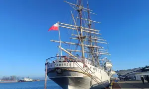 Duma polskiego żeglarstwa, żaglowiec "Dar Pomorza", cumuje przy nabrzeżu. Biało-czerwona flaga dumnie powiewa na maszcie.