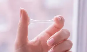 Eine Hand hält eine zähe, klare Substanz, die anzeigt, dass es sich um Ausfluss nach Eisprung handelt.