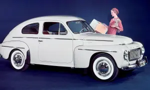 En vit Volvo PV 444 med en kvinna och en hund bredvid.