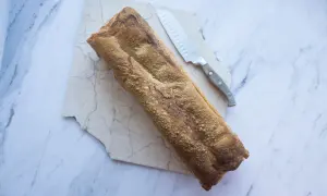 Chrupiący keto chleb na marmurowej desce, gotowy do pokrojenia.