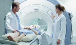 Pacjentka leży w aparacie do rezonansu magnetycznego, a lekarze przygotowują badanie z kontrastem.