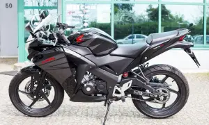 Czarny motocykl Honda CBR 125R z automatyczną skrzynią biegów, gotowy do jazdy po mieście.