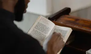 Modlitwa o cud finansowy. Ksiądz czyta z księgi modlitwę o Boże błogosławieństwo i wsparcie.