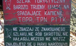 Tabliczka na szlaku turystycznym: "Bardzo trudny, uwaga na spadające kamienie". Niżej: "Nie zbaczaj ze szlaku, nie rób skrótów, nie hałasuj, niczego nie niszcz. Znajdujesz się w Parku Narodowym". Przełęcz Karb.