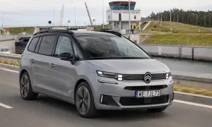 Srebrny Citroen Picasso jedzie drogą obok kanału. W tle widoczna wieża kontrolna i podniesiony most.